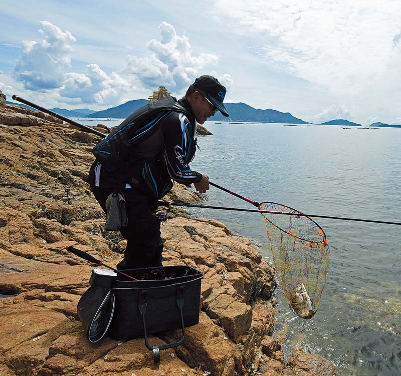 タモ網へ収まったチヌが海面から上がり、その姿を見て笑みをこぼす圓山