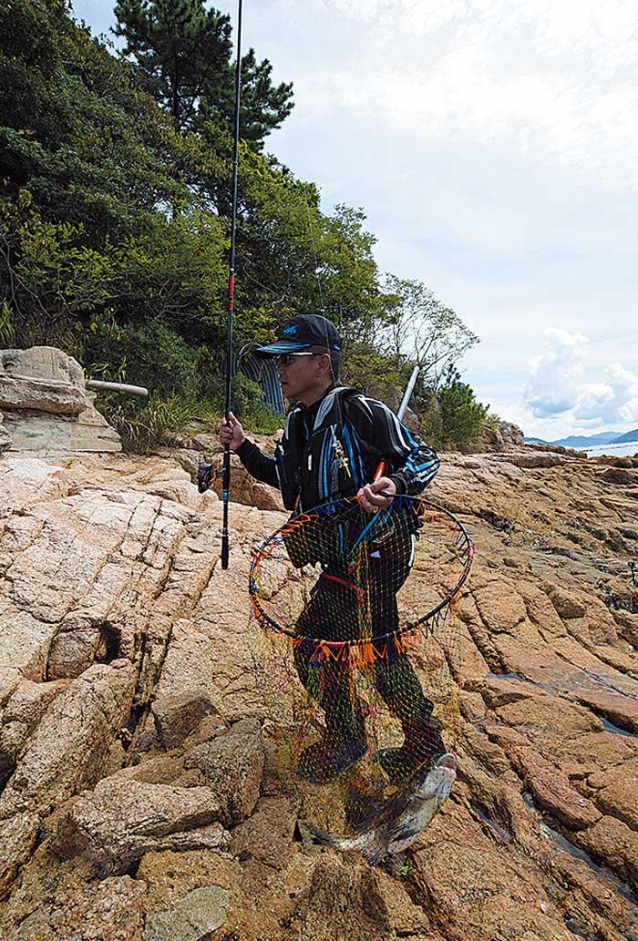 アテンダーⅢと魚を納めたタモ網を両手に、軽快に磯を駆ける圓山