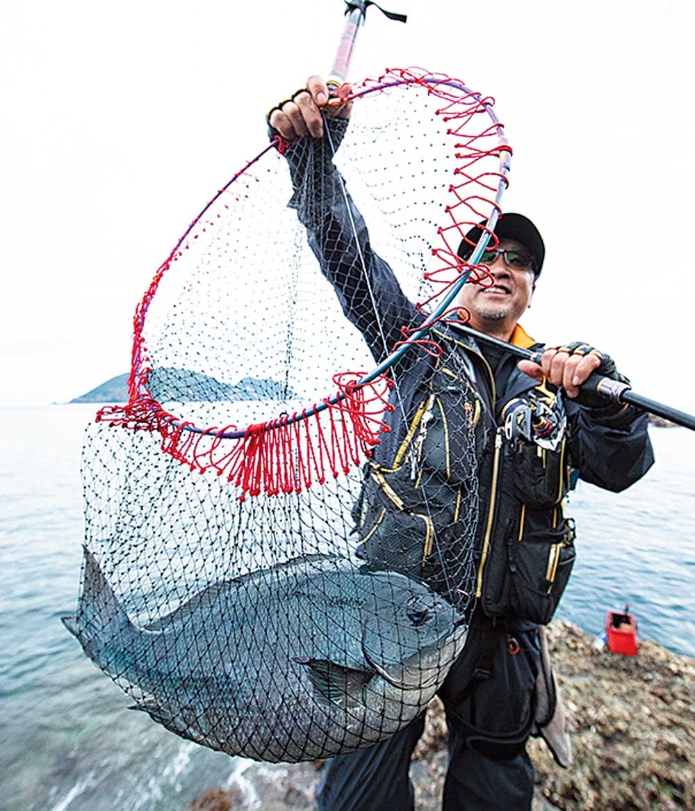 47cmの尾長グレが収まるタモ網を掲げ、笑顔の西森