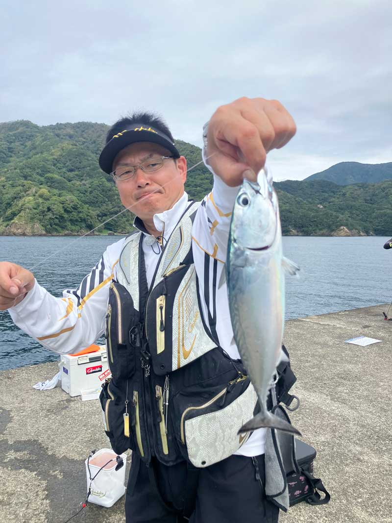 ラインを持ち、釣り上げた魚を掲げる鷲尾