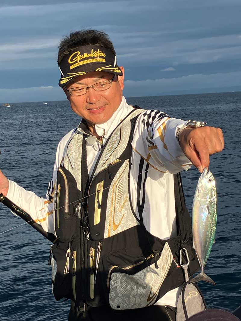 釣り上げた魚を掲げ、見つめる鷲尾