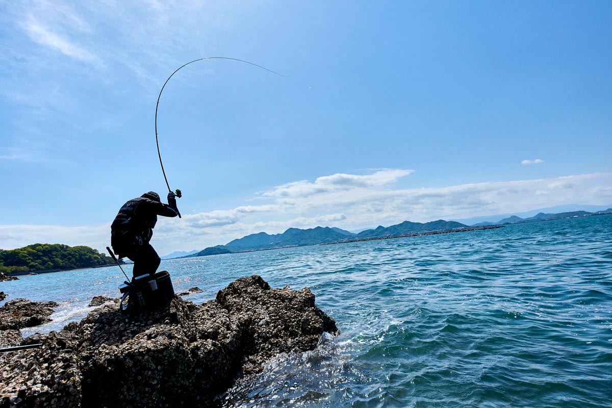 大きく湾曲する竿を立て、中腰の姿勢で魚とやりとりする波多