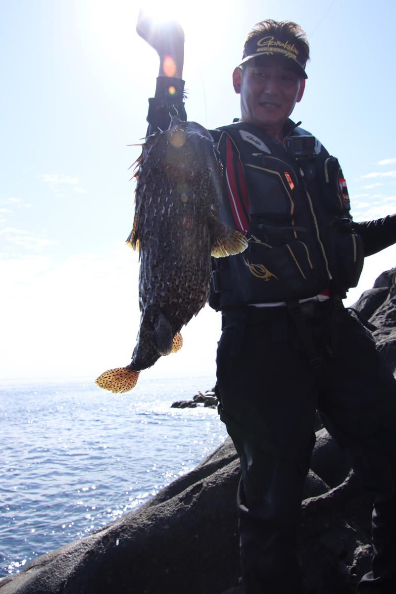 大物を釣り上げた直後の早田。ラインを持った手を頭上に挙げ、笑顔を見せる。