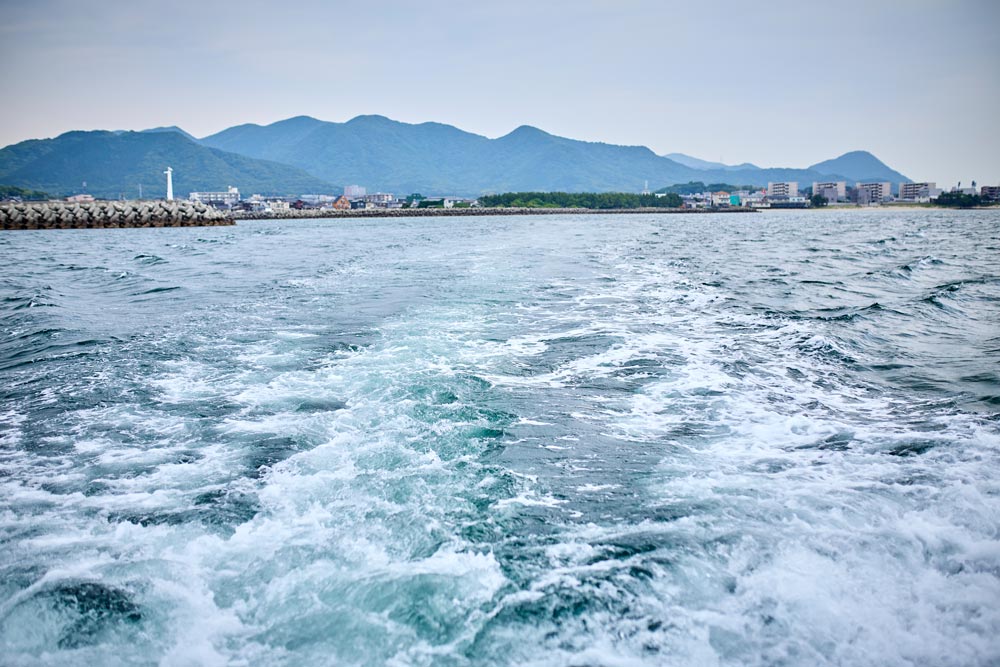 船が走った後の海。奥に漁港が見える
