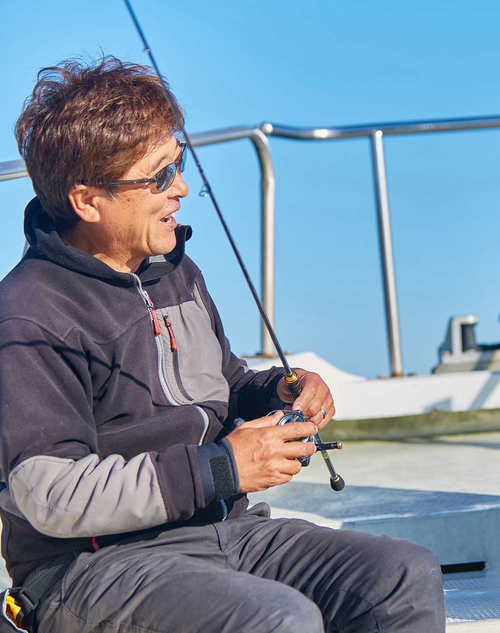 釣り竿を手に笑顔で会話をしている男性