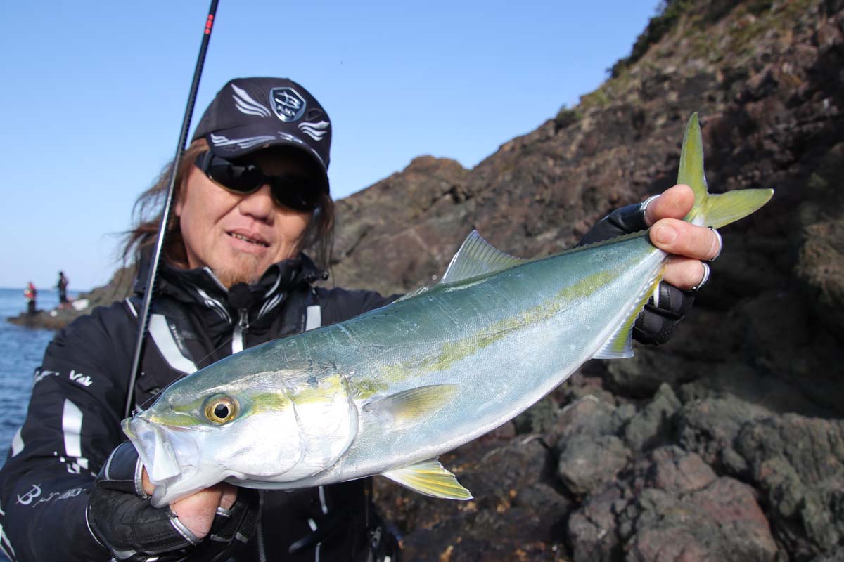 釣り上げたハマチを両手に持ち、掲げる前西