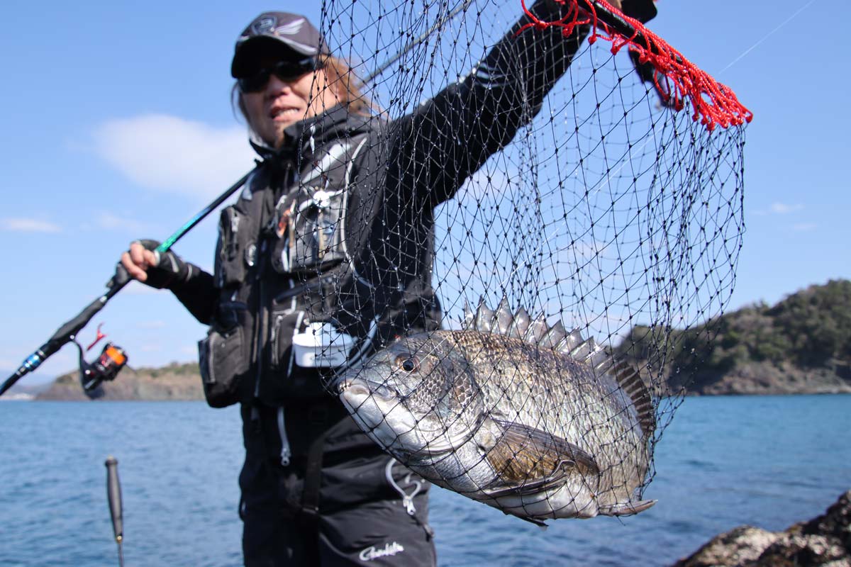 タモ網を掲げ、釣り上げたチヌを見せる前西