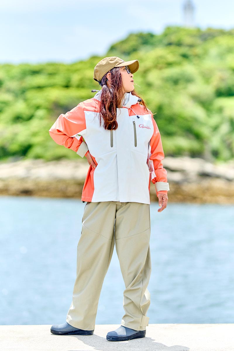 サーモンピンク/ベージュカラーのレインスーツを着用した女性モデル