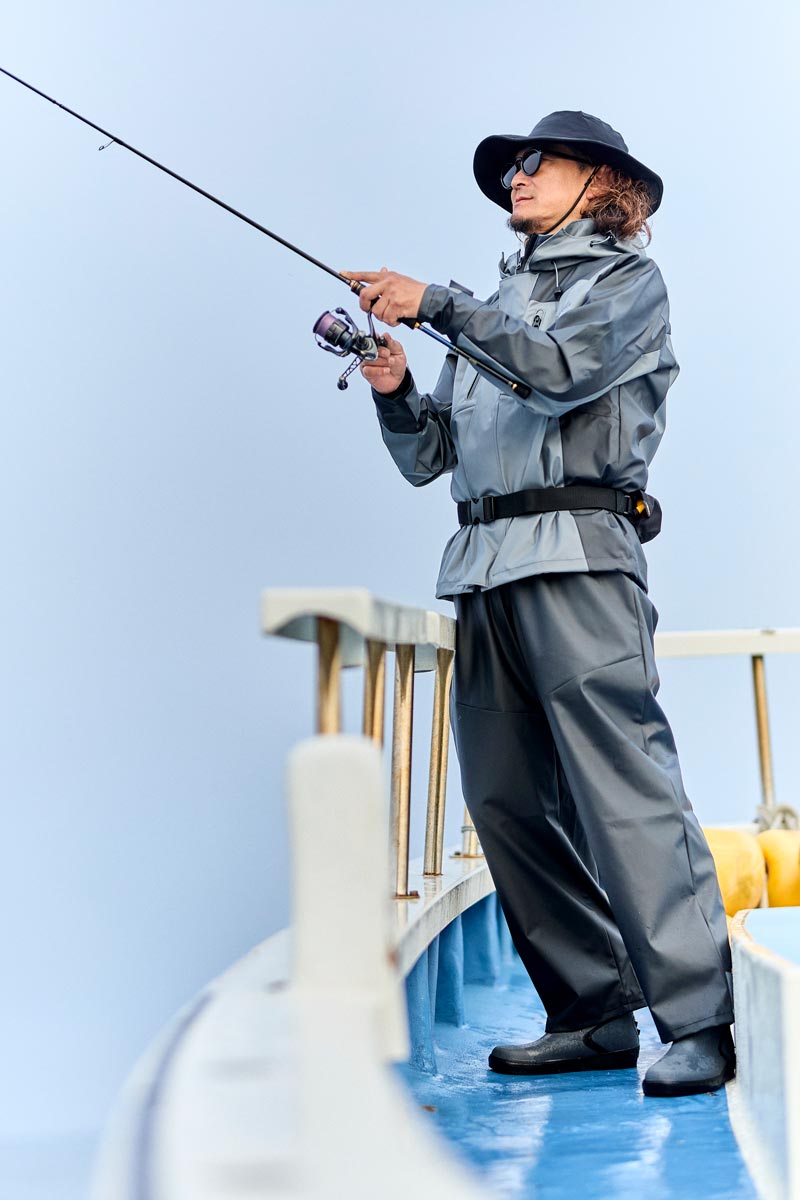 グレー/ブラックカラーのレインスーツを着用した男性モデル