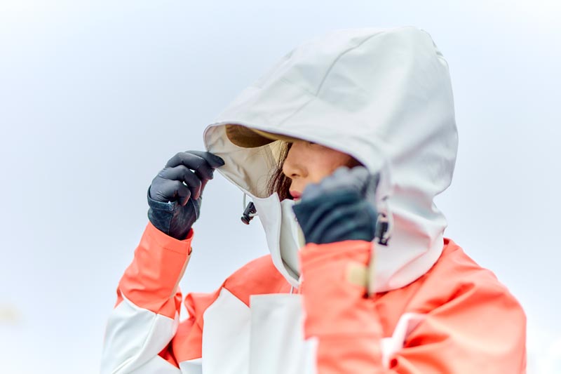 レインスーツのフードを被る女性