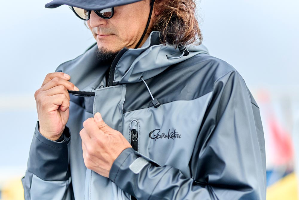 レインスーツの首元を軽く開いて見せる男性モデル