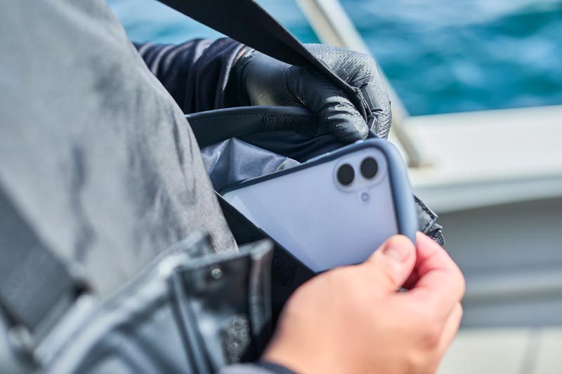 サロペットパンツの内側ポケットに、スマートフォンを収納する様子