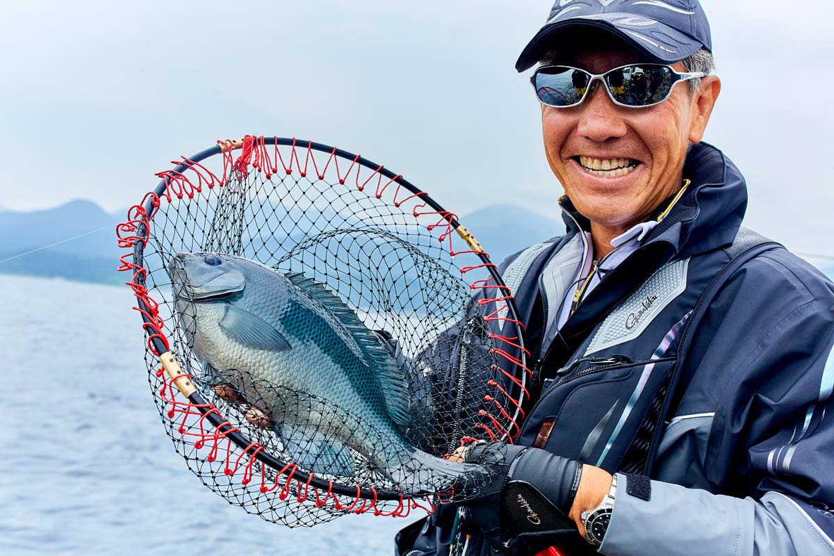 タモ網に収まった口太を胸元で掲げ、満面の笑みを見せる久保野