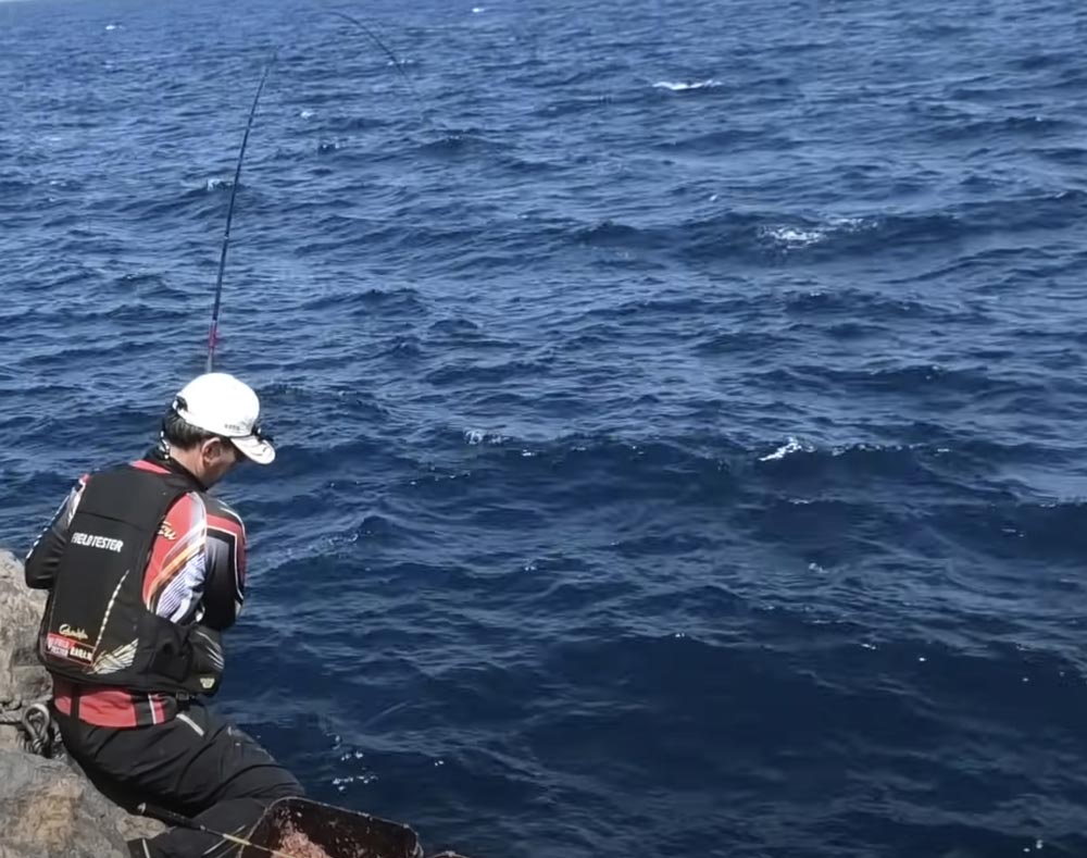 大きくしなる竿を操作し、魚とやりとりする敷地の背中
