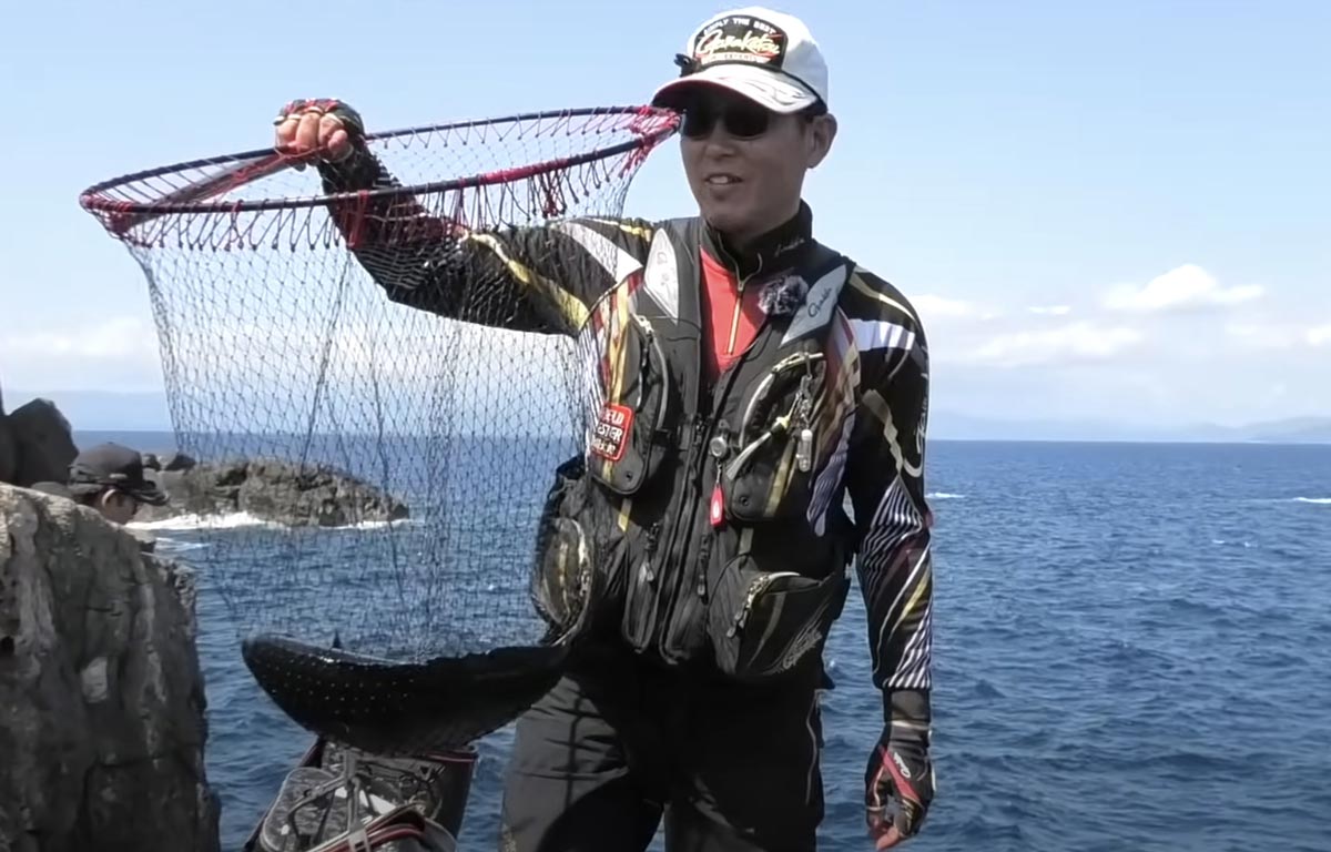 タモ網を掲げ、収まった尾長グレを笑顔で見つめる敷地