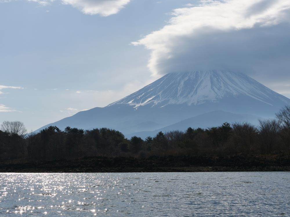 湖の向こうに見える富士山。山頂部分は厚い雲に覆われている。