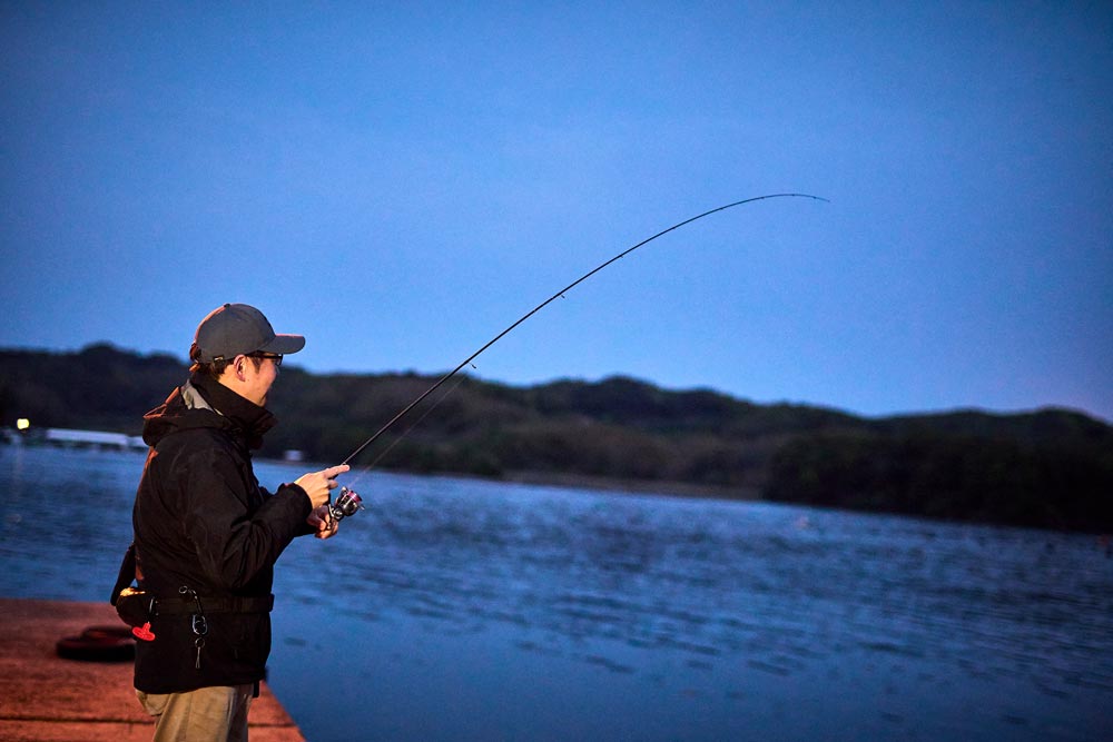 薄暗い堤防で釣りを楽しむ藤原