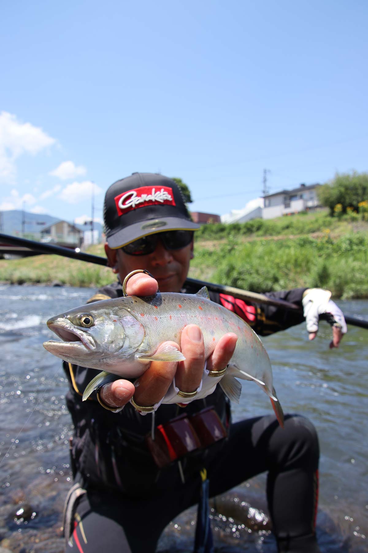 釣り上げたアマゴを右手に持ち、掲げる吉村