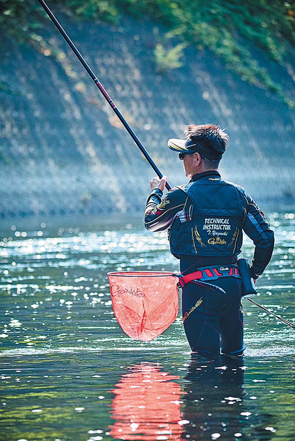 川の中へ入り、竿を操作する谷口の背中