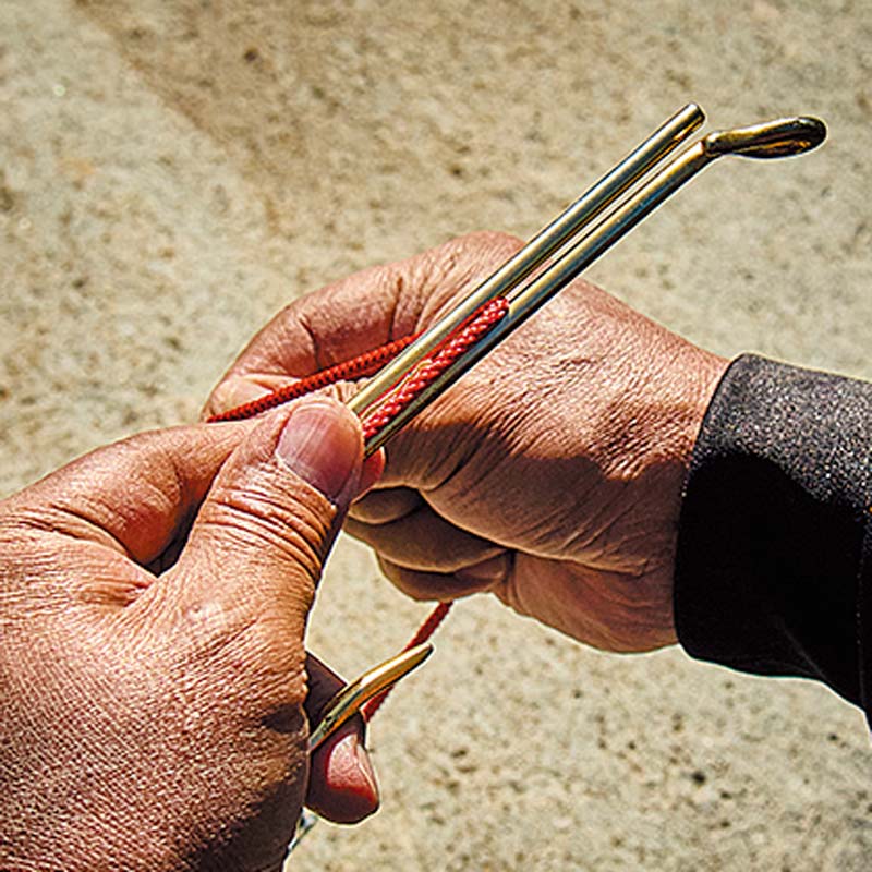 大型の鈎模型を使用し、ハリスに見立てた赤い紐を結び付けている様子