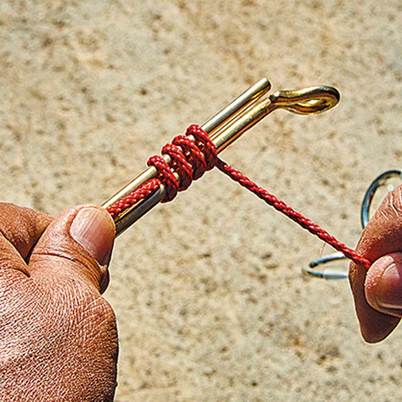 大型の鈎模型を使用し、ハリスに見立てた赤い紐を結び付けている様子