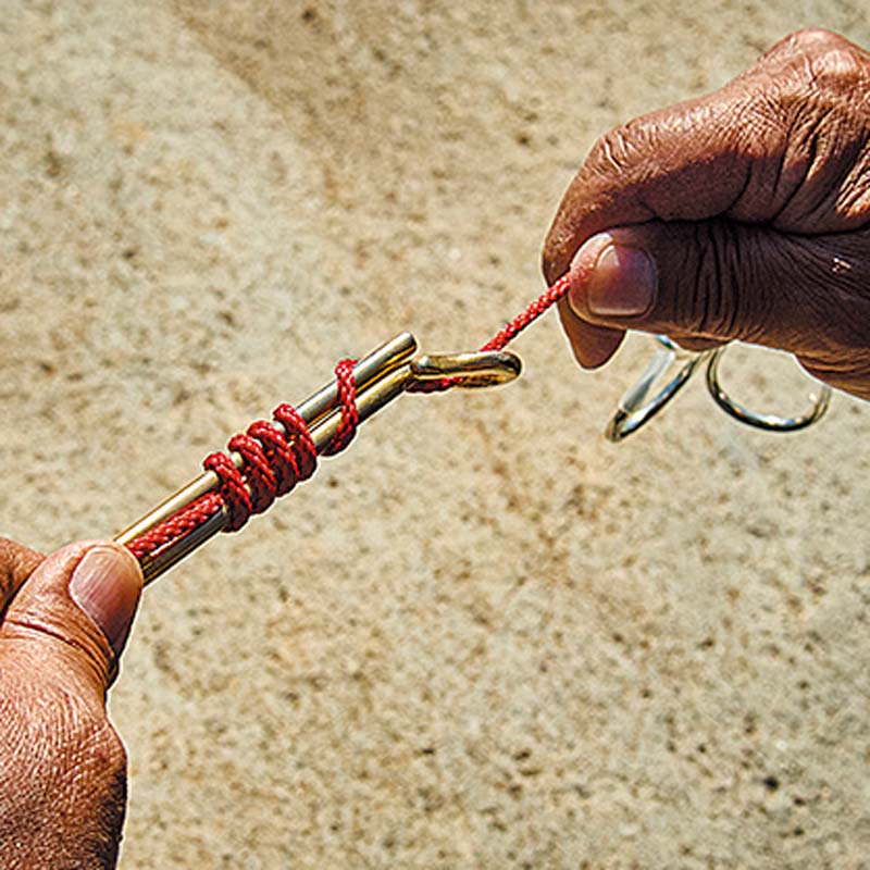 大型の鈎模型を使用し、ハリスに見立てた赤い紐を結び付けている様子