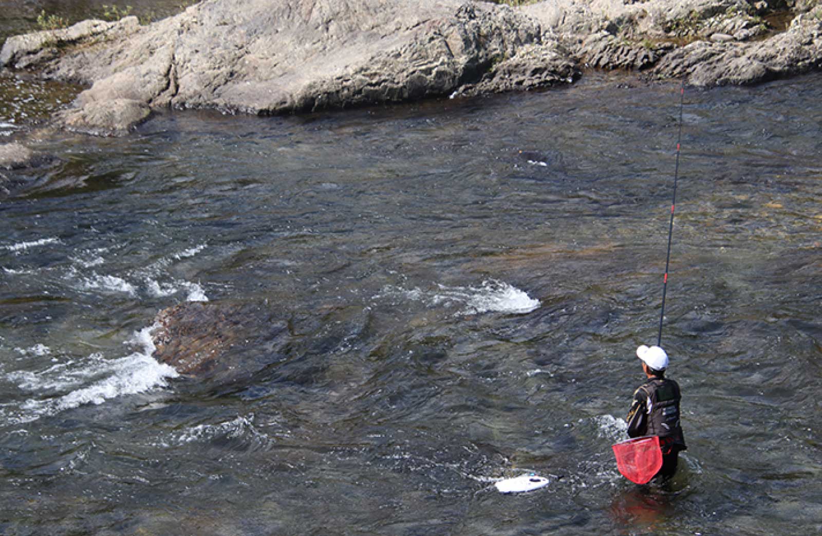 流れのある渓流入り、竿を立てて釣りをする廣岡の空撮