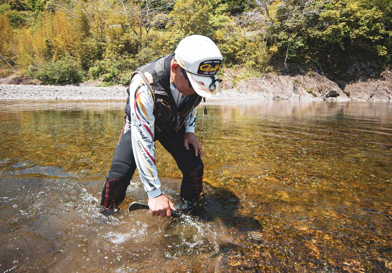 川の中に入り、作業をする廣岡