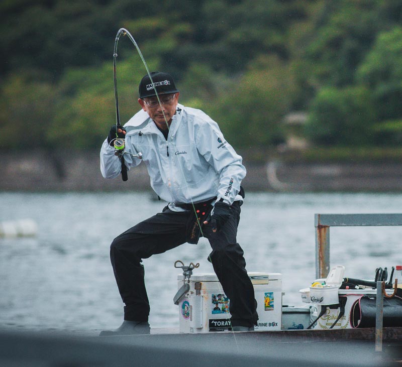 足を開いて腰を落とし、竿を引いて魚とやりとりする林