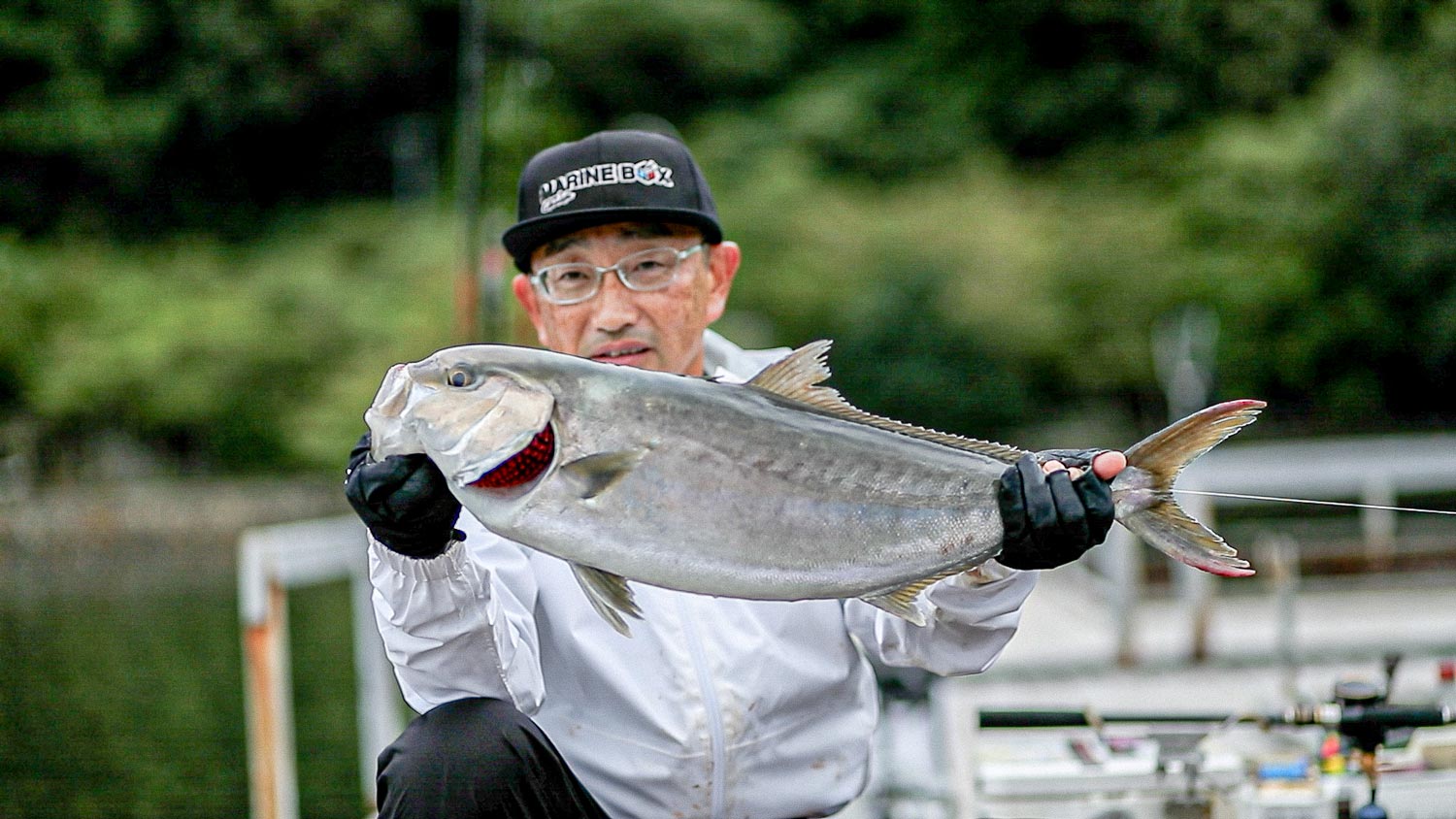 釣り上げた魚を両手で持ち、掲げる林