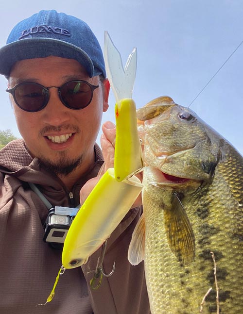ルアーで釣り上げた魚を持ち上げ、笑顔の赤松