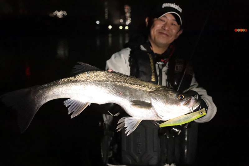 釣り上げたシーバスを手に、笑顔を見せる久保田。シーバスの唇にはルアーが掛かったまま。
