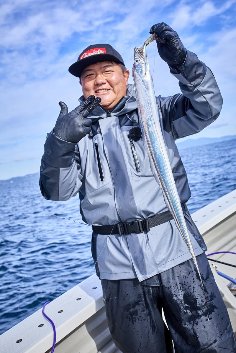 釣り上げたタチウオを左手で持ち、ポーズを決める中山
