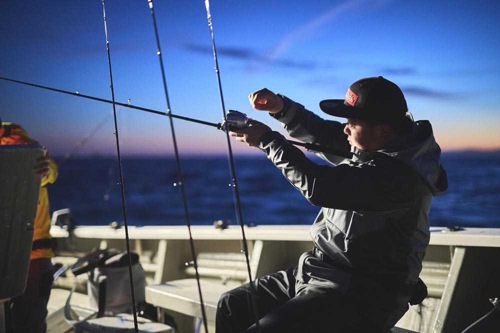 陽が沈み手元が暗くなってきた中、船上で竿を操作する中山。