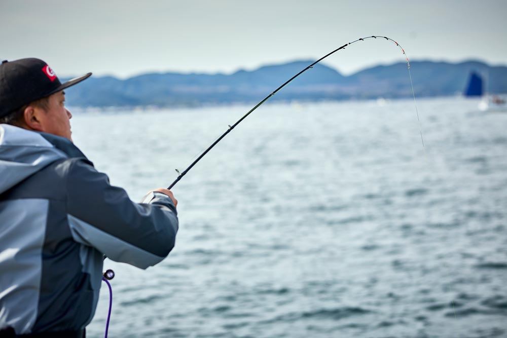 弧を描く竿を操作する中山を背後から捉えた写真