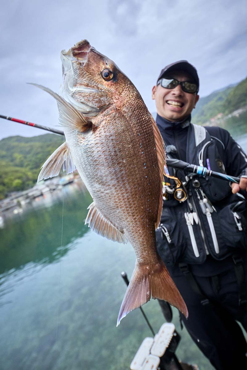 釣り上げたマダイを掲げ、笑顔を見せる沖永