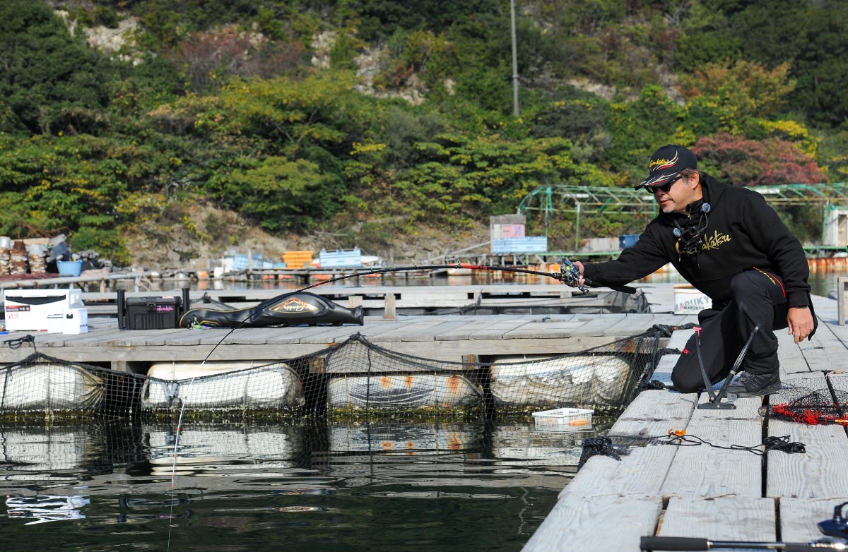 大きな弧を描く竿を、しゃがみながら片手で操作する沖長