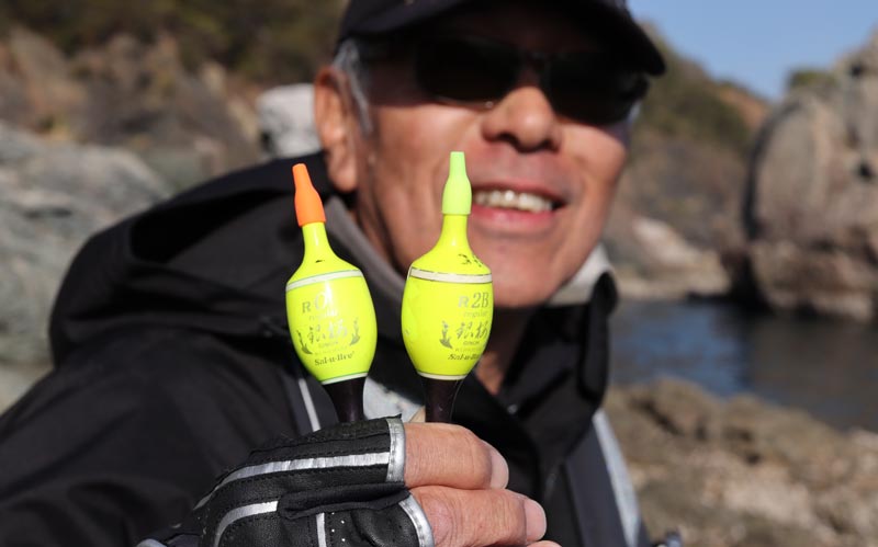 2種類の浮きを手に持ち、笑顔で見せる中西