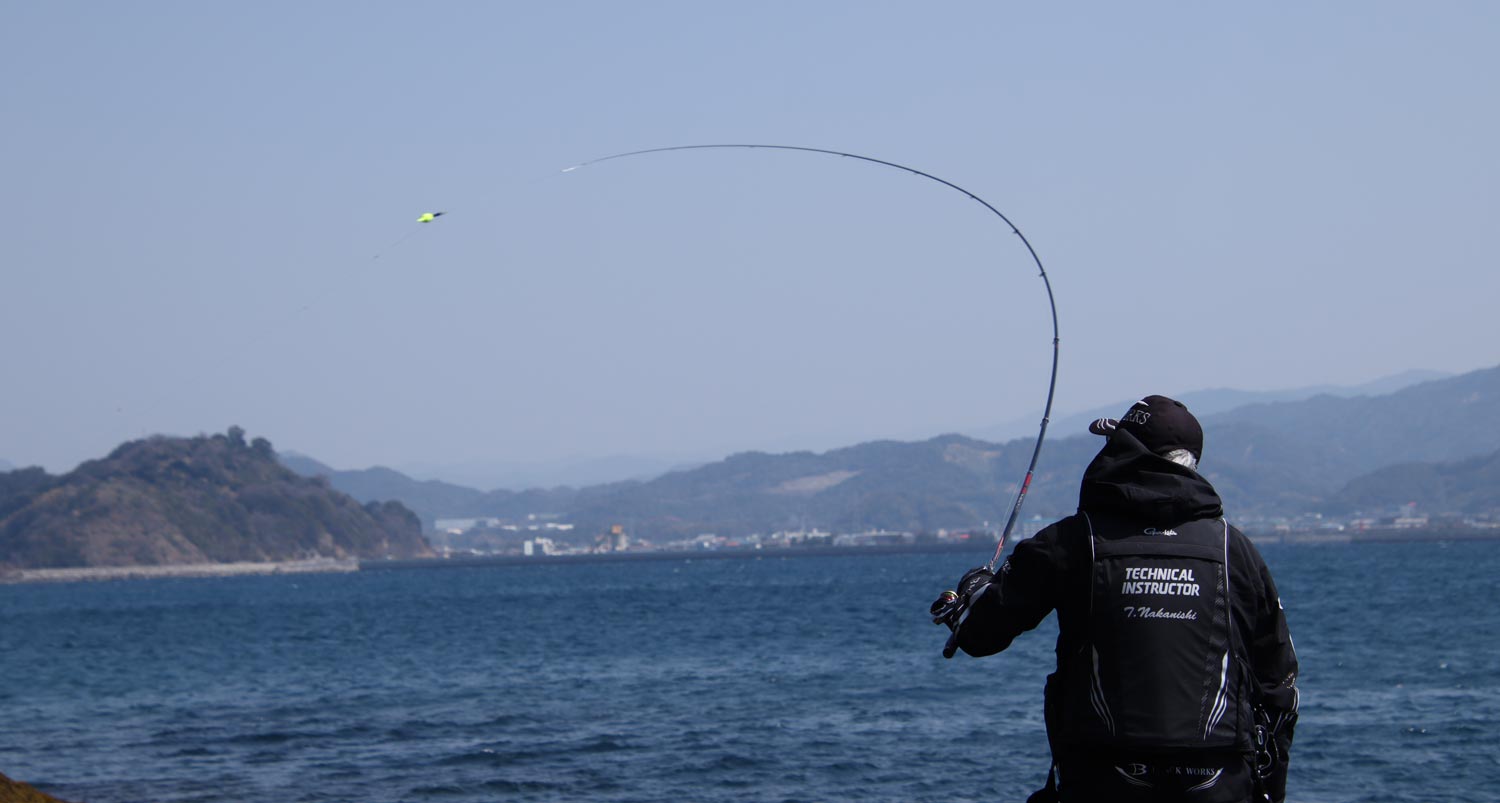 竿を振り、仕掛けを投入する中西の背中