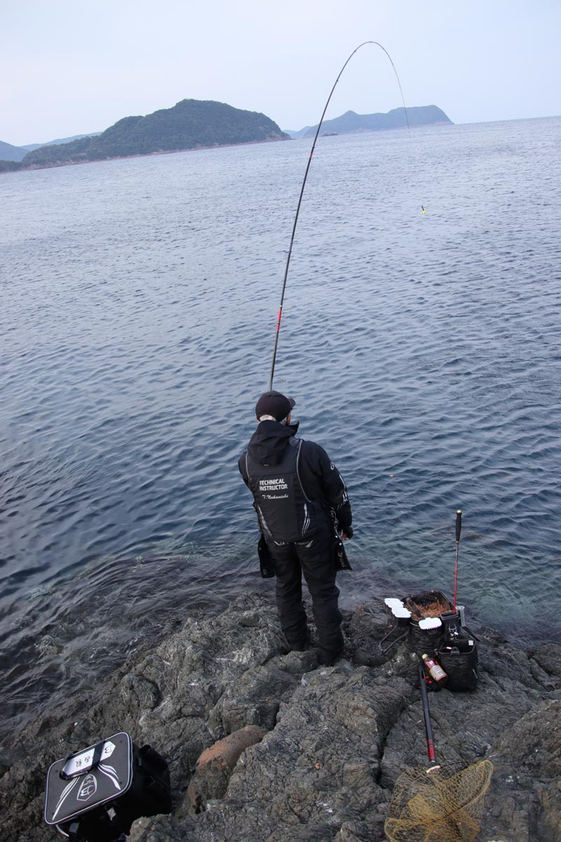 大きく弧を描く竿を操作する中西の背中