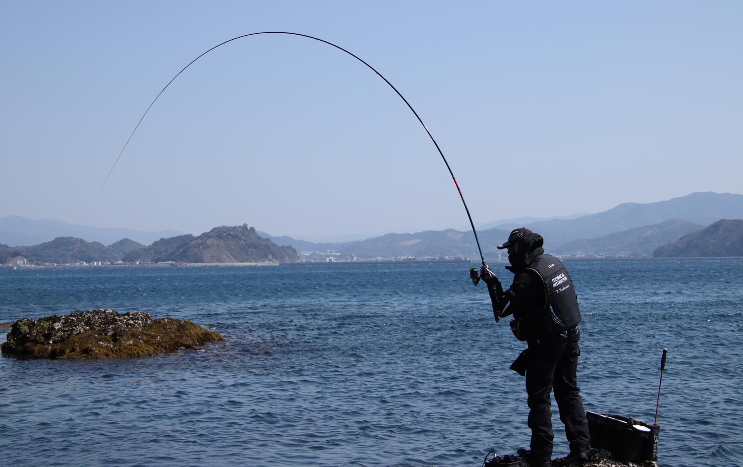 大きく弧を描く竿を操作する中西の背中