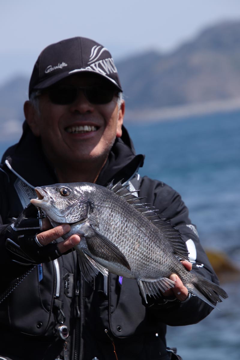 両手で釣り上げたチヌを持ち、笑顔の中西