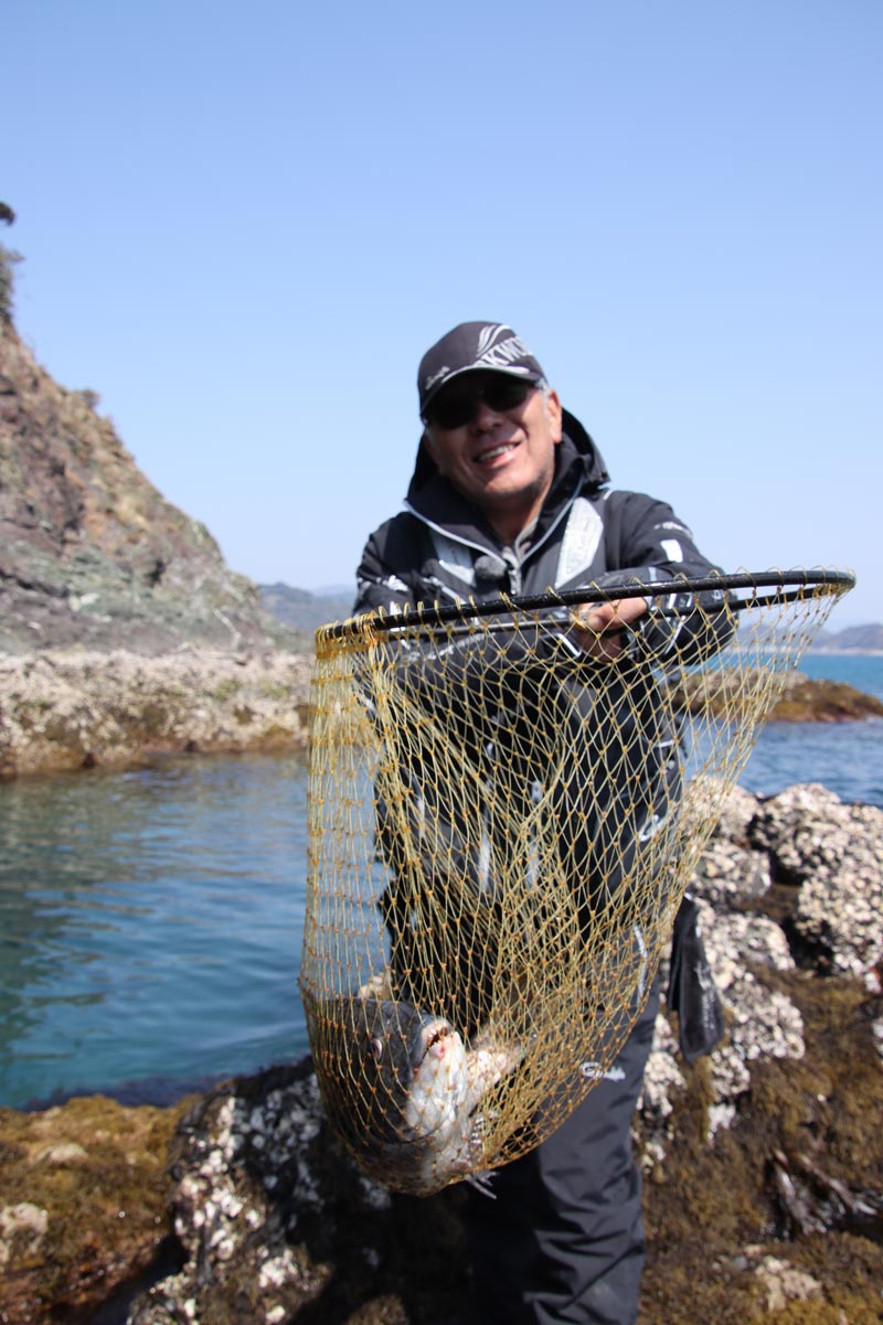 チヌが収まったタモを持ち上げ見せる中西