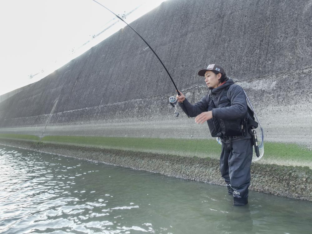 すねが半分程浸かる深さの海に入り、釣りをする黒神