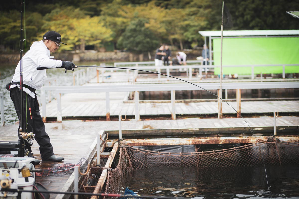 右手で竿を持ち、魚とやりとりする男性