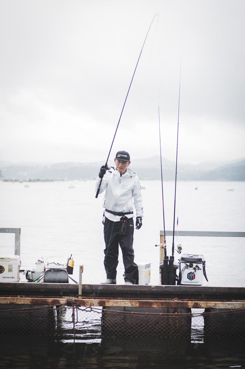 右手で竿を立て、魚とやりとりする男性