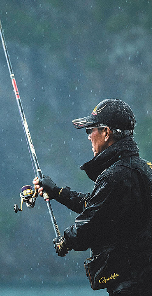雨の中、竿を両手でしっかりと持つ久保野の姿