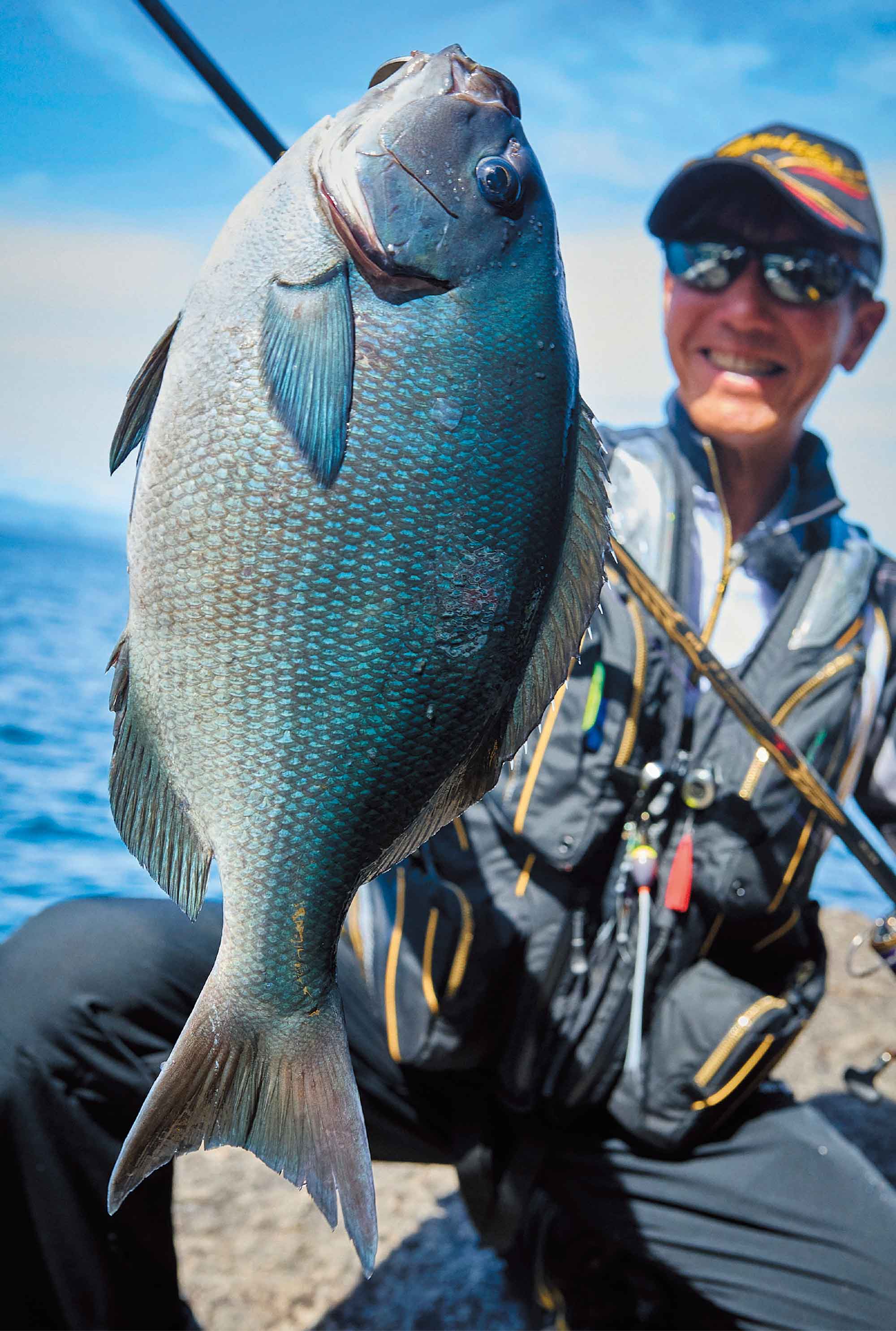 丸々肥えた40cmの尾長グレを片手で掲げ、満面の笑みを見せる久保野