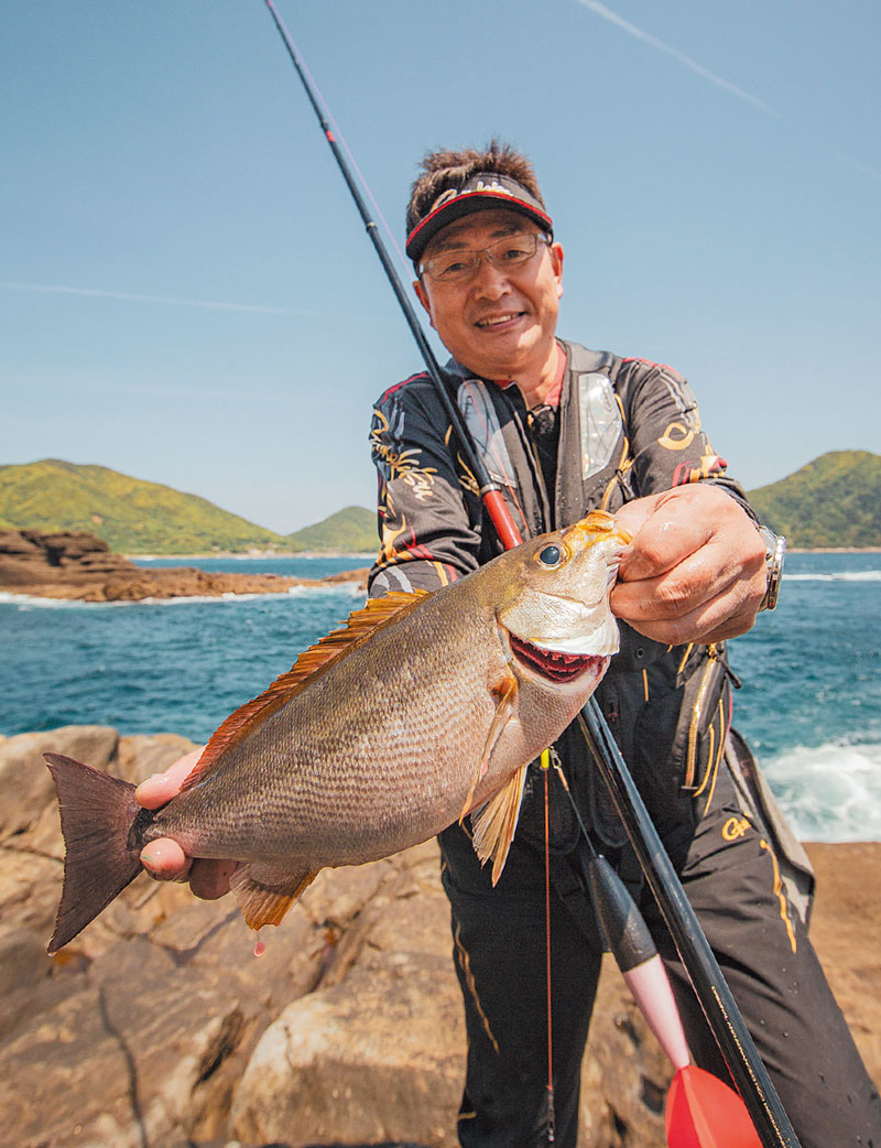 釣り上げたイサキを持ち、笑顔の鷲尾