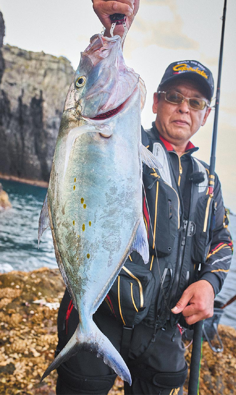 釣り上げたナンヨウカイワリを掲げ、微笑む高園